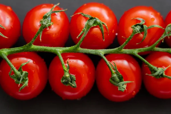 Vue rapprochée des tomates cerises humides sur fond noir — Photo de stock