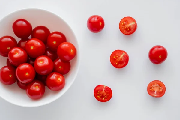 Vue du dessus des tomates cerises dans un bol et sur fond blanc — Photo de stock