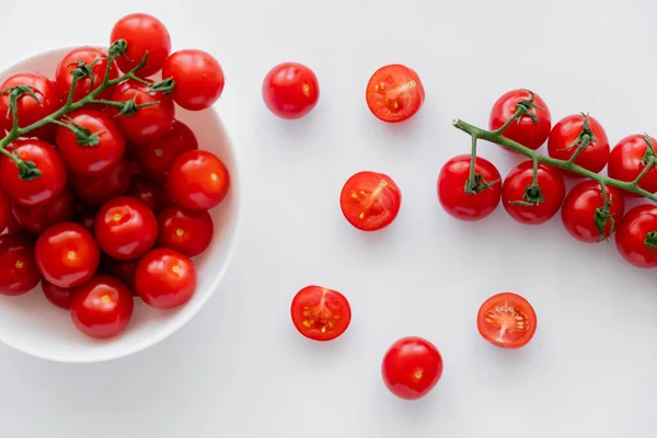 Vue du dessus des tomates cerises naturelles sur les branches dans un bol sur fond blanc — Photo de stock