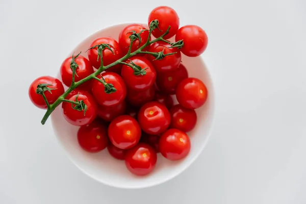 Draufsicht auf frische Kirschtomaten auf Zweig in Schüssel isoliert auf weiß — Stockfoto