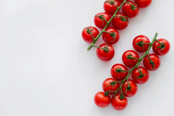Vue du dessus des tomates cerises fraîches mûres sur des branches sur fond blanc — Photo de stock