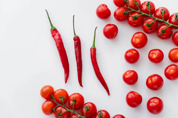 Draufsicht auf Chilischoten in der Nähe von frischen Kirschtomaten auf weißem Hintergrund — Stockfoto