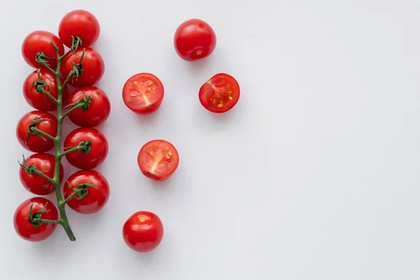 Вид зверху на цілі та нарізані вишневі помідори на білому тлі — стокове фото