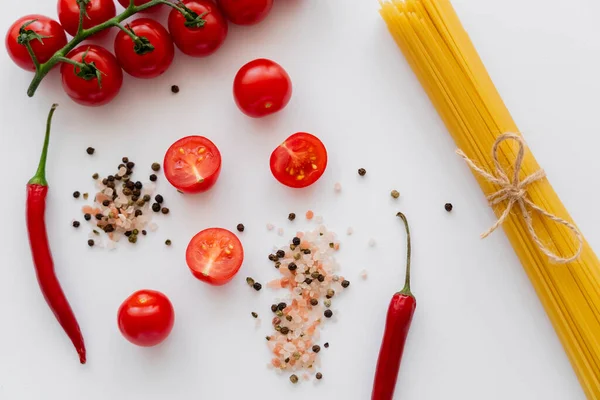 Vue du dessus des macaronis crus et des légumes frais près des épices sur fond blanc — Photo de stock