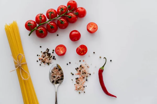 Draufsicht auf reifes Gemüse in der Nähe von Spaghetti und Gewürzen im Löffel auf weißem Hintergrund — Stockfoto