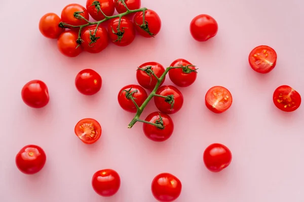 Vista superior de tomates cherry orgánicos sobre ramas sobre fondo rosa - foto de stock