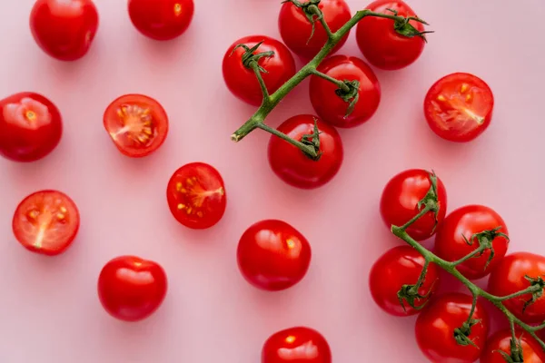 Vista superior de tomates cherry maduros sobre ramas sobre fondo rosa - foto de stock