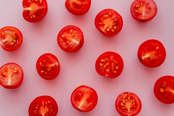 Vista superior de tomates cherry cortados sobre fondo rosa - foto de stock