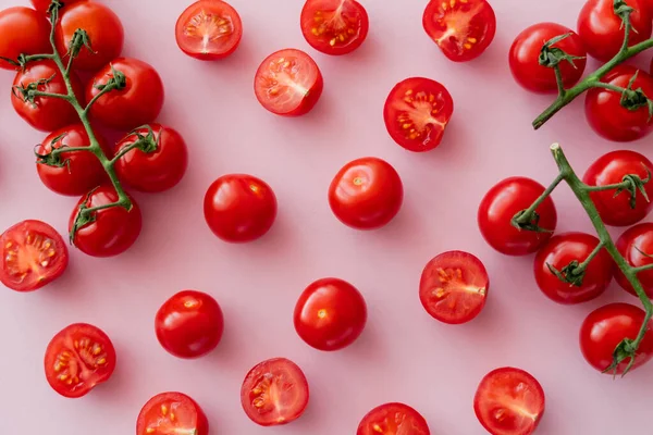 Draufsicht auf natürliche Kirschtomaten auf Zweigen auf rosa Oberfläche — Stockfoto