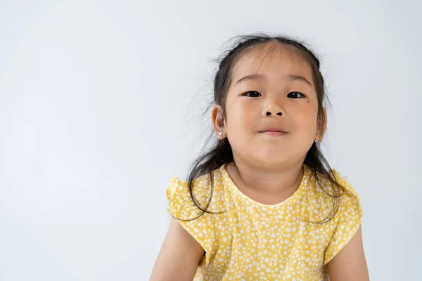 Ritratto di compiaciuto prescolastico e asiatico ragazza guardando fotocamera isolato su grigio — Foto stock