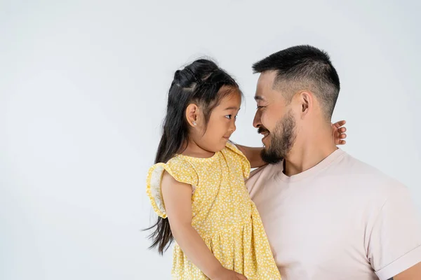 Vista lateral de feliz padre e hija mirándose aislados en gris - foto de stock