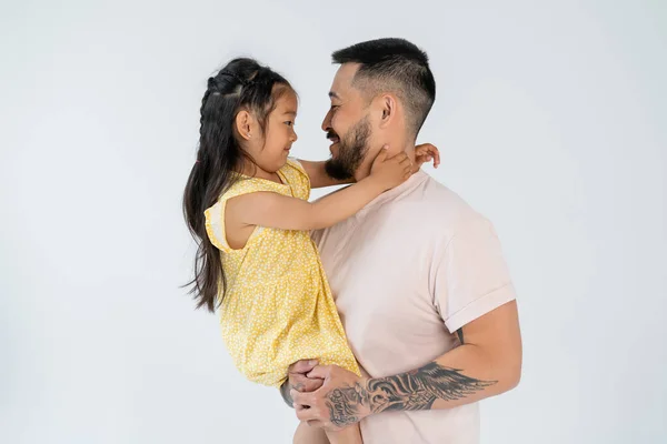 Vista lateral de alegre padre e hija mirándose aislados en gris - foto de stock