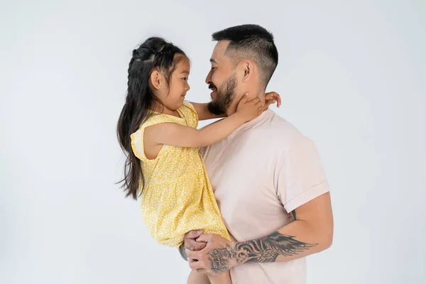 Vista laterale di padre allegro e figlia che si guardano l'un l'altro isolati su grigio — Foto stock