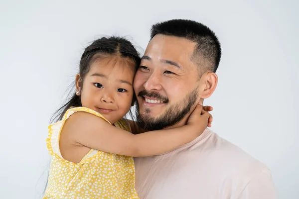Весела азіатська дочка обіймає щасливого батька ізольовано на сірому — стокове фото