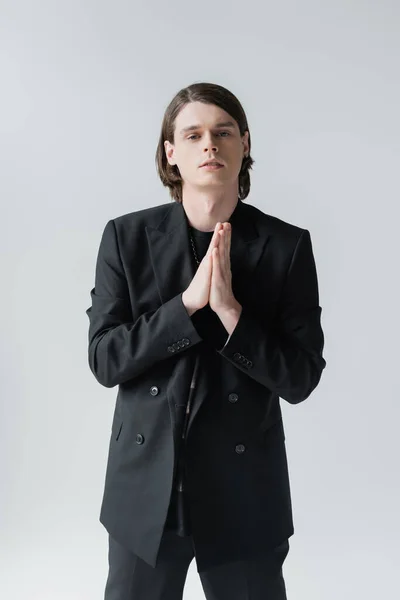 Young man in suit posing and looking at camera isolated on grey — Stock Photo