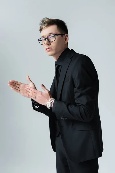 Homem elegante de terno e óculos posando isolado no cinza — Fotografia de Stock