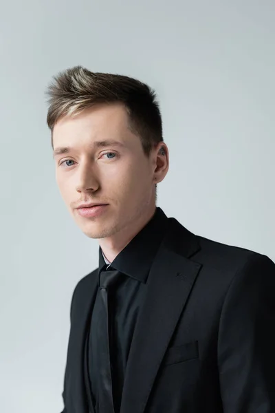 Portrait of young man in black formal wear isolated on grey — Stock Photo