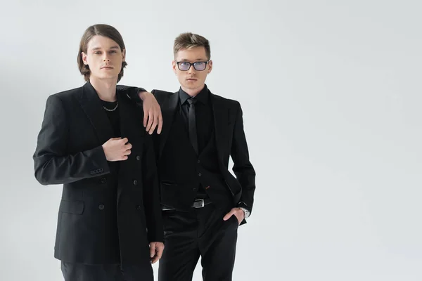 Young gay couple in formal wear posing isolated on grey — Stock Photo