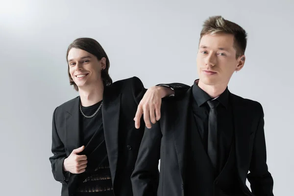 Positive gay standing near boyfriend in formal wear isolated on grey — Stock Photo