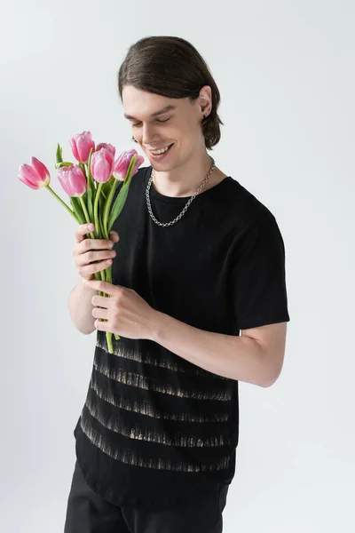 Feliz hombre elegante con tulipanes aislados en gris - foto de stock