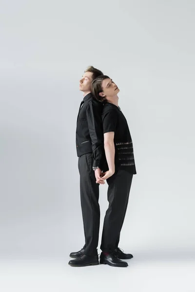 Volle Länge des gleichgeschlechtlichen Paares, das die Hände auf grauem Hintergrund hält — Stockfoto