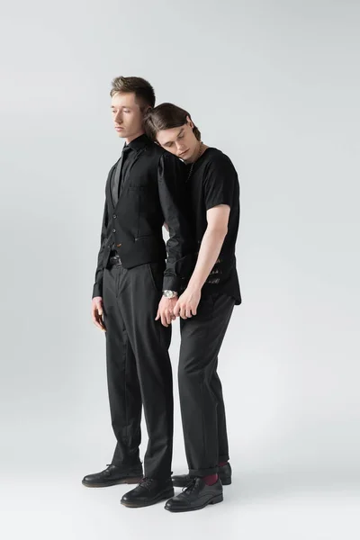 Full length of young gay couple holding hands on grey background — Stock Photo