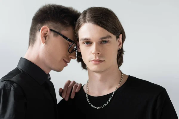 Brunette gay looking at camera near boyfriend in eyeglasses isolated on grey — Stock Photo