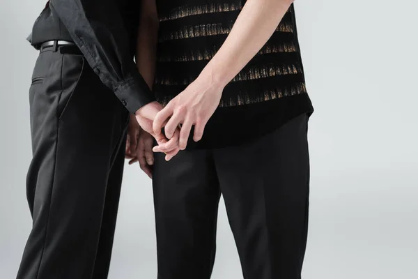 Обрезанный вид молодой гей-пары, держащей руки в изоляции на сером — стоковое фото