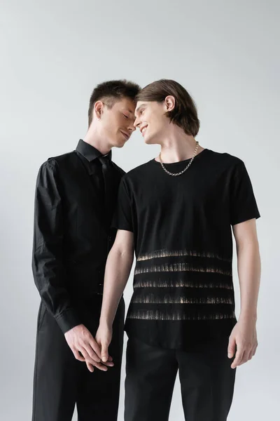 Positivo casal do mesmo sexo tocando as mãos isoladas no cinza — Fotografia de Stock
