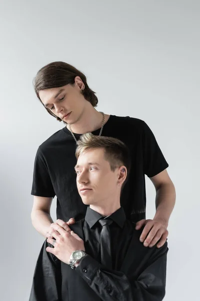 Young man embracing tattooed boyfriend isolated on grey — Stock Photo