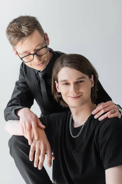 Lächelnd Homosexuell in formeller Kleidung umarmt und berührt Hand des Freundes isoliert auf grau — Stockfoto