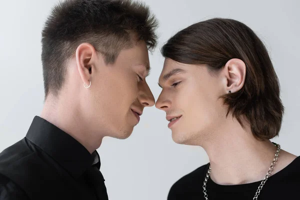 Vue latérale d'un jeune couple gay souriant isolé sur gris — Photo de stock