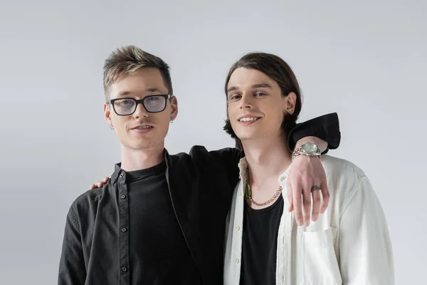 Positif gay couple câlins et regarder caméra isolé sur gris — Photo de stock