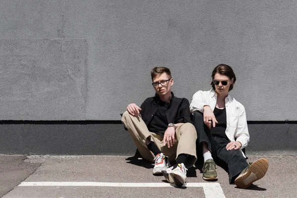 Молода гомосексуальна пара сидить біля будівлі на відкритому повітрі — стокове фото