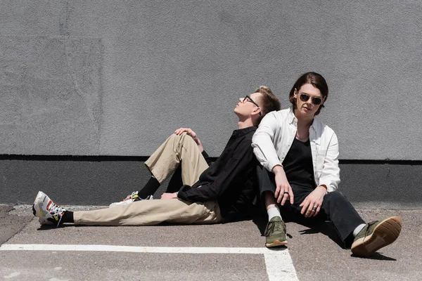 Young same sex couple sitting near building on urban street — Stock Photo