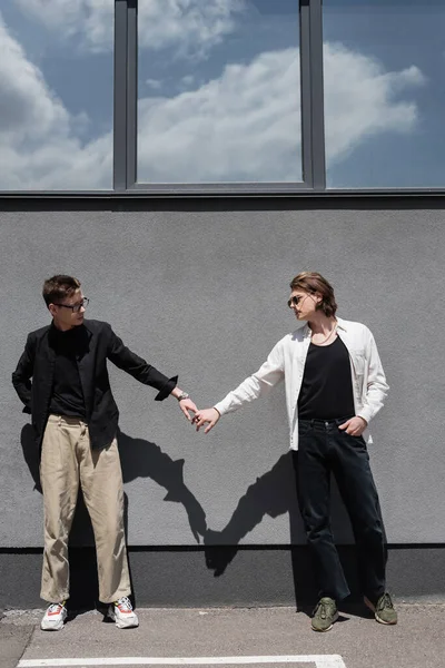 Young gay couple holding hands near building outdoors — Stock Photo