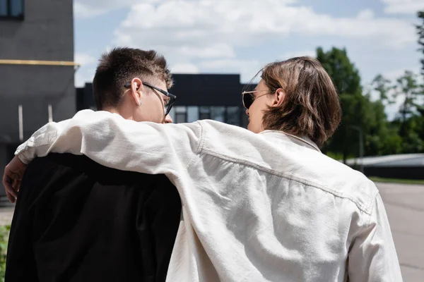 Side view of man in sunglasses hugging boyfriend on urban street — Stock Photo