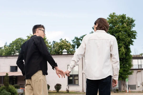 Pareja homosexual cogida de la mano en la calle urbana - foto de stock