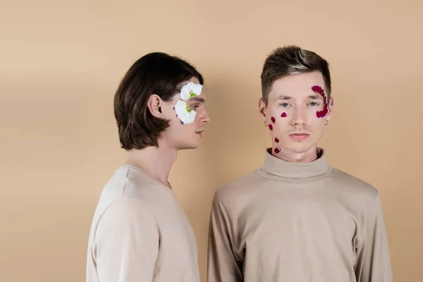 Same sex couple with petals on faces isolated on beige — Stock Photo