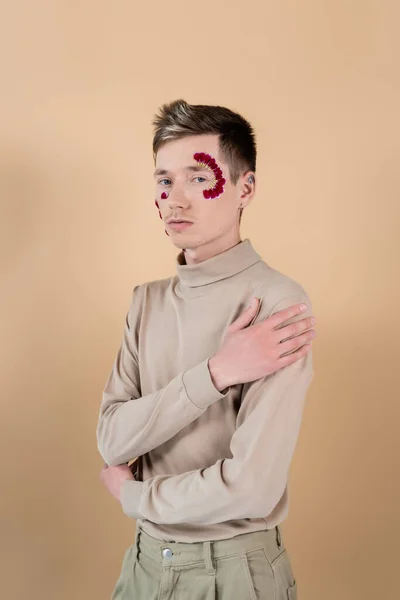 Portrait of man with petals on face looking at camera isolated on beige — Stock Photo