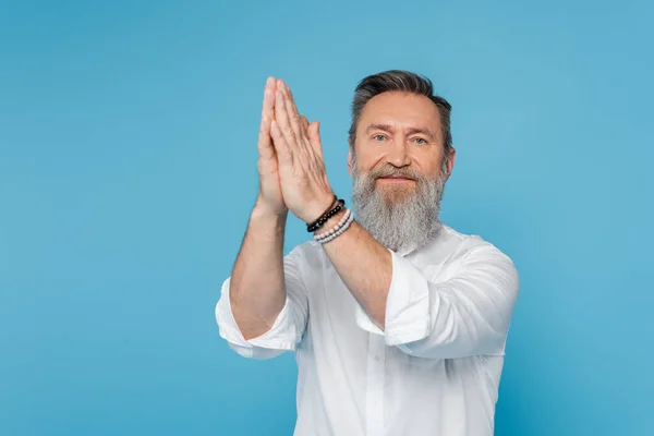 Senior master guru in beaded bracelets showing anjali mudra gesture isolated on blue — Stock Photo