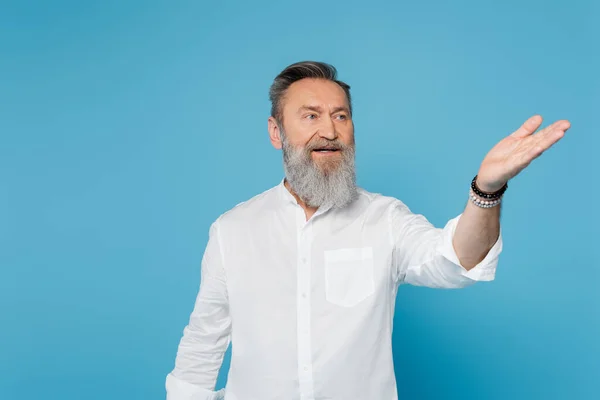 Senior bearded guru man looking away and pointing with hand isolated on blue — Stock Photo