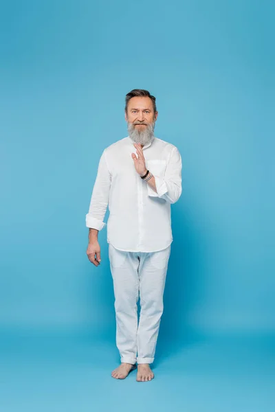 Full length of master guru in white clothes showing blessing gesture on blue — Stock Photo