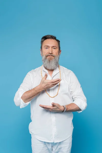 Senior master guru showing energy gesture near chest and looking at camera isolated on blue — Stock Photo