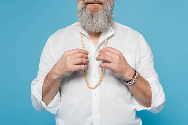 Partial view of master guru touching beads while meditating isolated on blue — Stock Photo