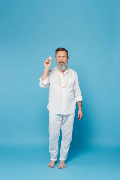 Volle Länge des barfuß Yogalehrers mit Selenitkristall auf blauem Hintergrund — Stockfoto