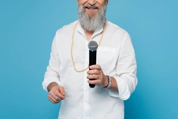 Partial view of bearded motivational coach talking in microphone isolated on blue — Stock Photo