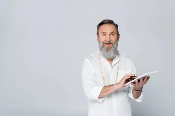 Bearded motivational coach with digital tablet looking at camera isolated on grey — Stock Photo