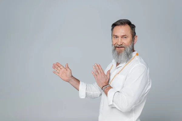 Gourou spirituel regardant caméra et pointant avec les mains isolées sur gris — Photo de stock