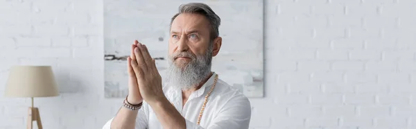 Senior Master Guru in Perlenarmbändern meditiert mit betenden Händen zu Hause, Banner — Stockfoto